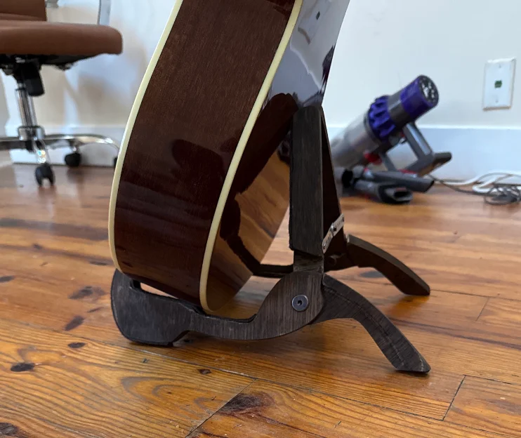 An acoustic guitar resting in the laser-cut wooden stand